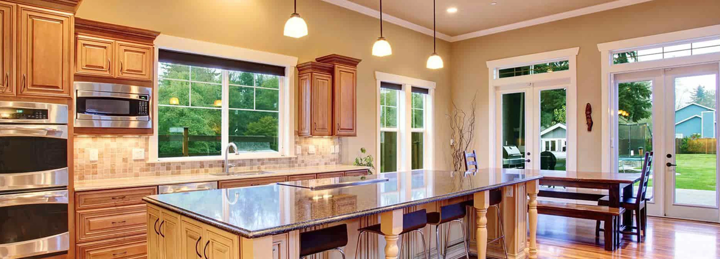 Kitchen island with brown dining room table and large windows.