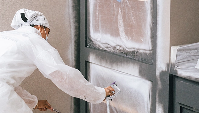 Five Star Painting professional refinishing a kitchen cabinet.