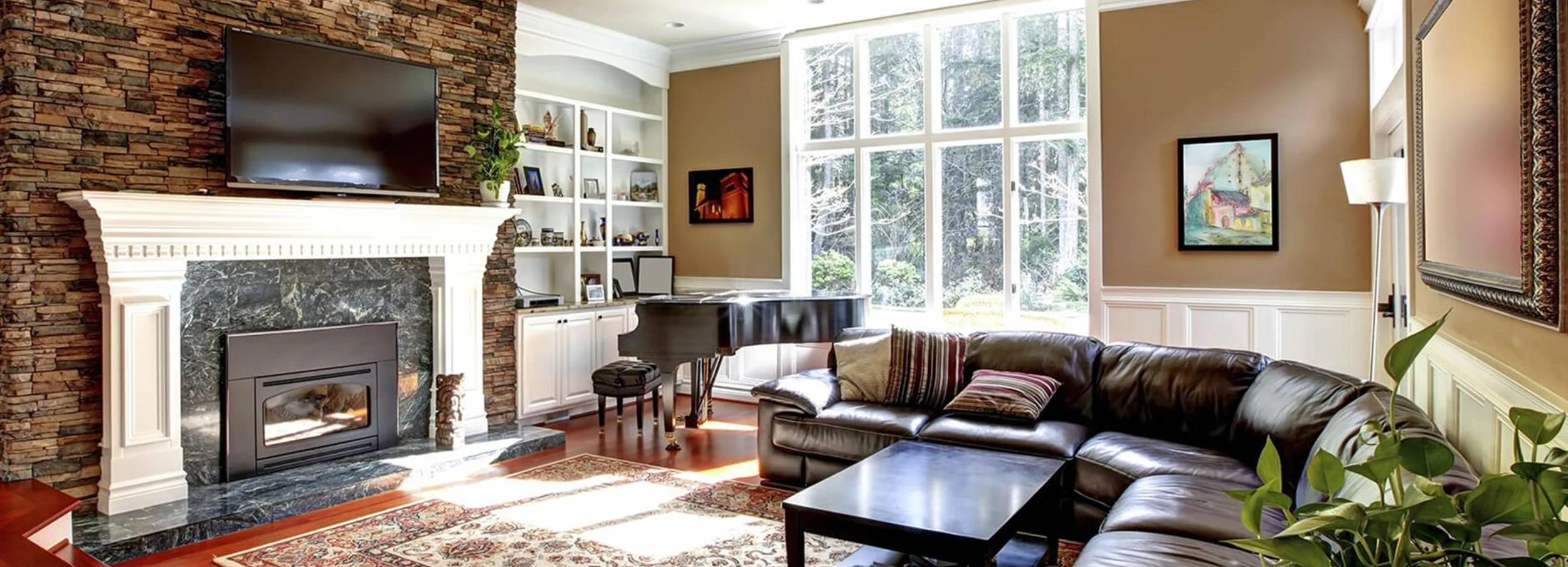 Brown themed living room with leather couch and brick fireplace.