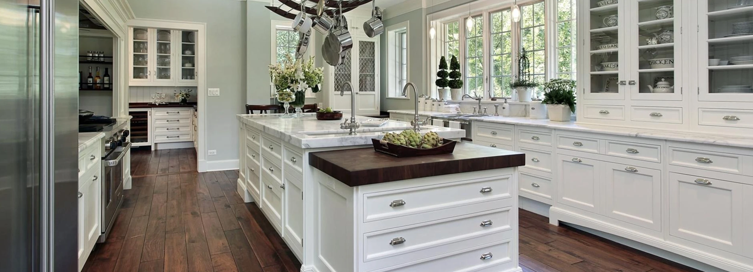 Marble top kitchen island in large, bright modern kitchen with dark hardwood floor and white cabinets professionally painted by Five Star Painting.