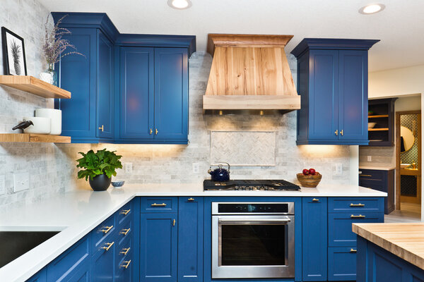 Modern kitchen with white countertops and blue cabinets.