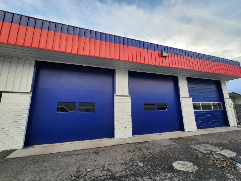 All Star Auto Glass Building with three large bay doors.  Roof line has two stripes going around the building.