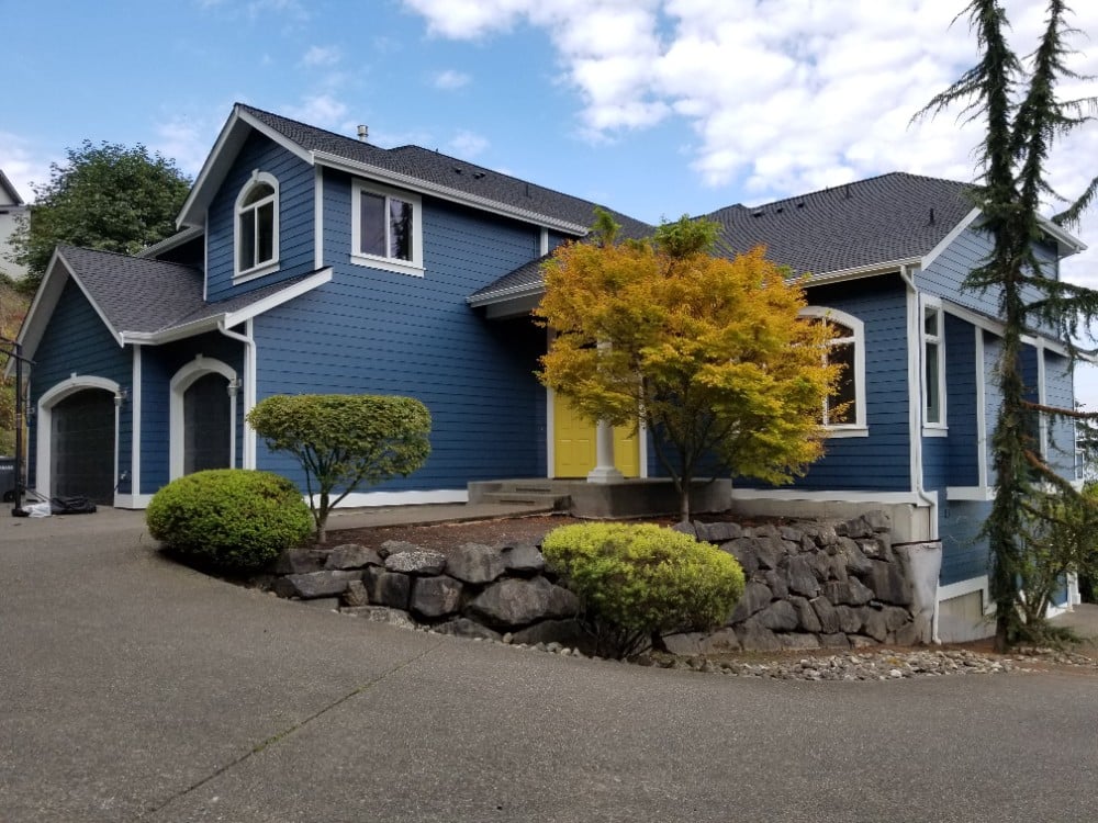 Two Story Home with landscaping, view of double entry door and two single garage doors