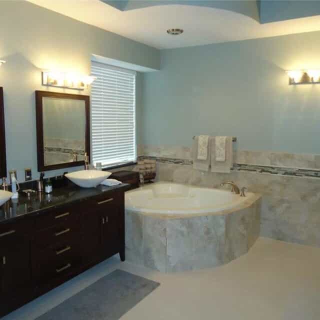 Blue bathroom with marble bathtub and brown cabinets