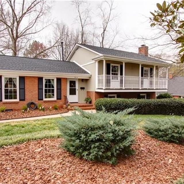 Brick and gray house with neat lawn and bushes