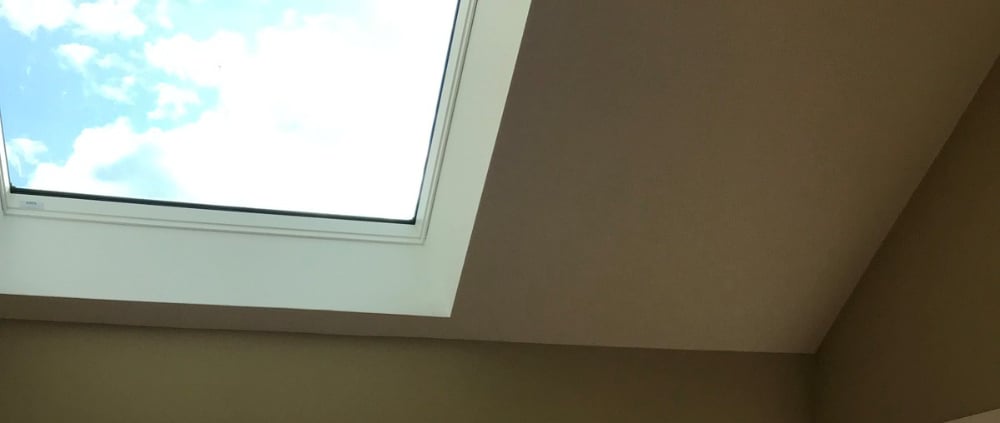 Tan walls white slanted ceiling with a large skylight