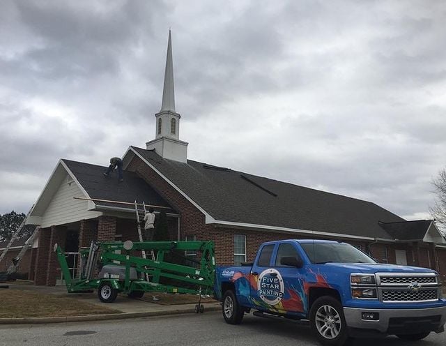 Church being painted with painters on roof