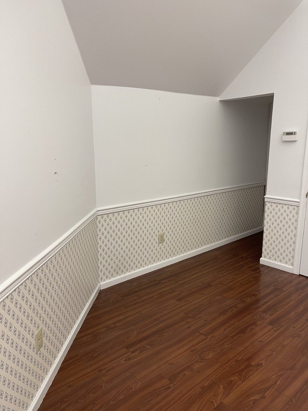 White office walls above chair rail wallpaper below brown wood floors high ceilings