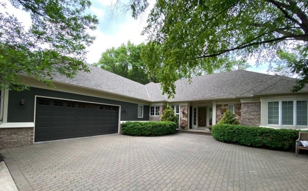 Green house with cream trim and dark green garage door