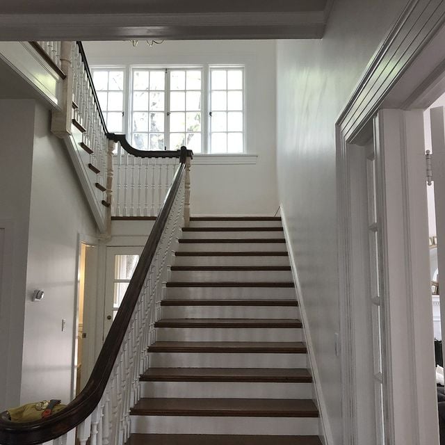 Extra white painted stairwell with deep wood accents on railing and stairs