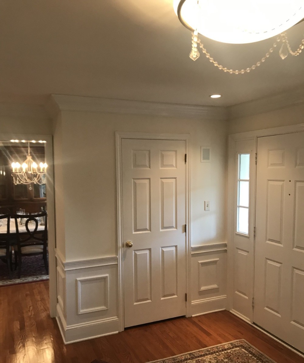 Entrance foyer will cream colored walls and bright white trim moldings medium brown wood flooring white doors