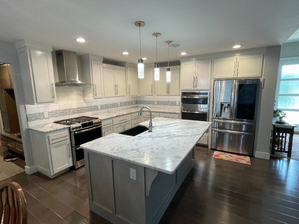 Interior kitchen cabinets and island repainted featuring backsplash and marble island