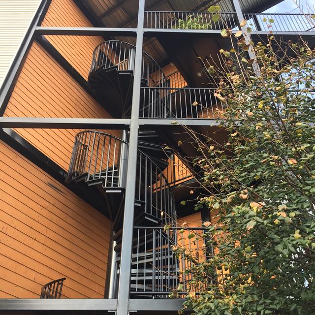 Painted black satin metal multi-story outdoor spiral staircase.