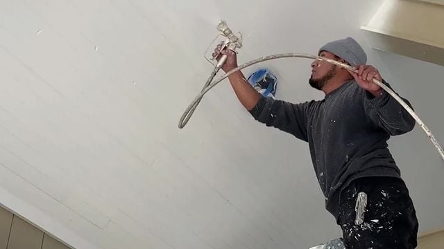 Staff spray painting a white ceiling