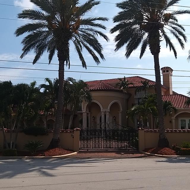 brown home with red tile roof and trees in front 