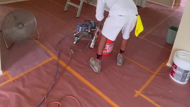 painter on top of painter's paper next to a red bucket