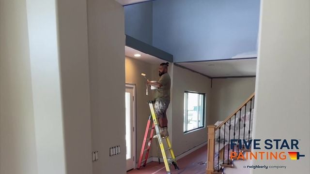 painter painting inside on a ladder