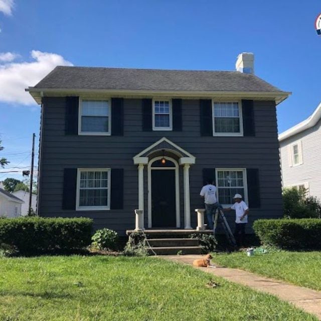 two painters painting a house navy blue with dark shutters