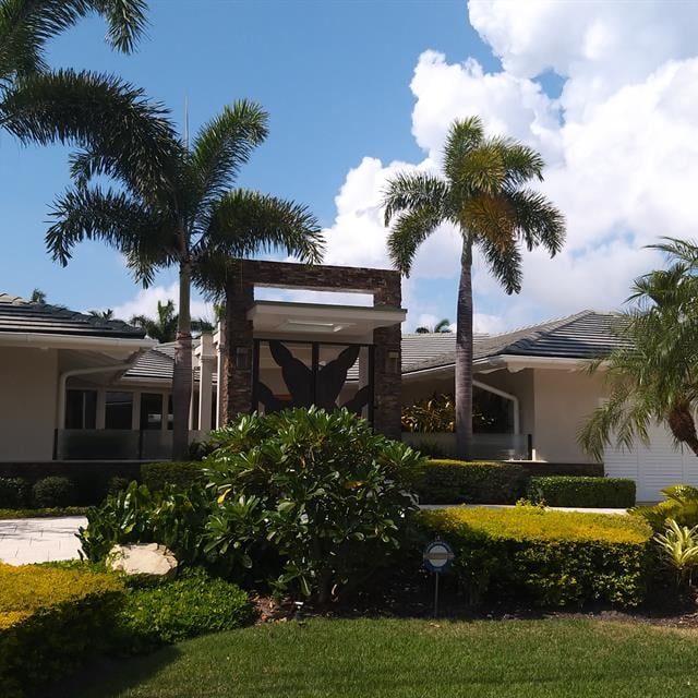 white home with bushes and trees in front 