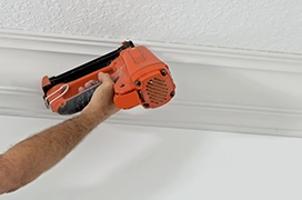 Protect Painters professional using a nail gun on crown moulding.