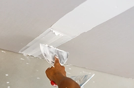 Protect Painters professional adding mud to repair drywall on a ceiling.