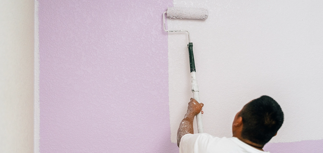 Protect Painters professional holding paint roller with back to camera.