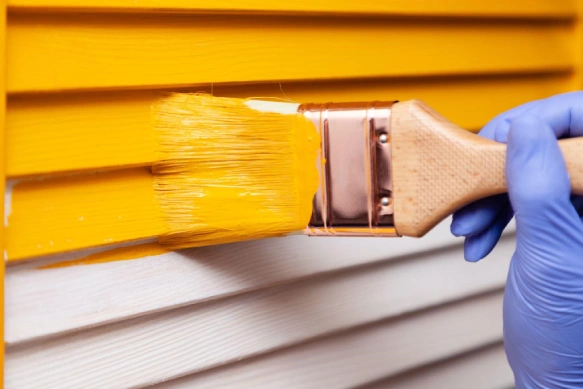 Image of someone painting vinyl siding.