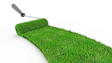 Photo of a gray-handled paint roller painting green grass onto the white background