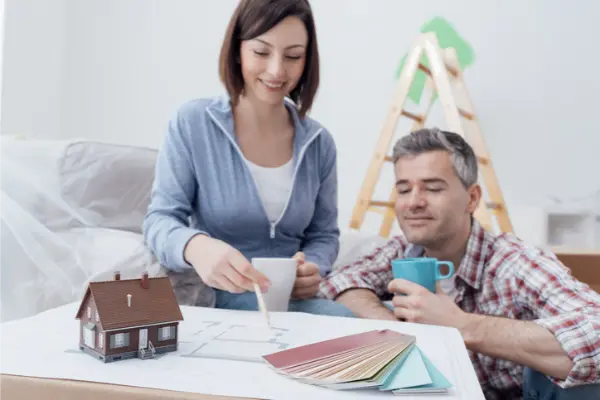 Couple reviewing floor plan and paint swatches with ladder in background.