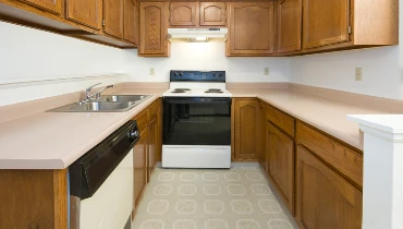 An outdated kitchen with laminate floors and Formica countertops.