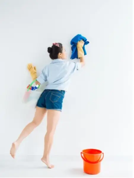 Woman wiping down a white wall with a towel.