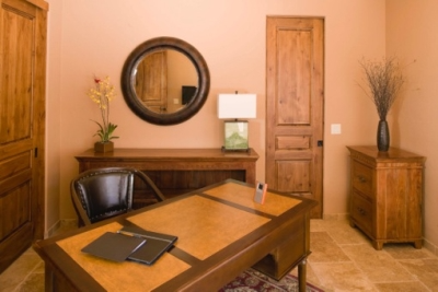 Beige walled office with medium colored wood furniture, dark wood accents and personal touches including a painting, flower arrangements and mirror Beige walled office with medium colored wood furniture, dark wood accents and personal touches including a painting, flower arrangements and mirror.
