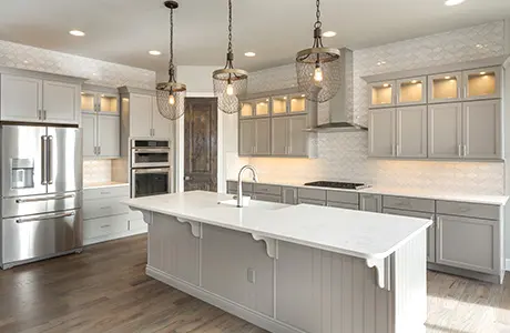 Large warmly lit kitchen with wood floors, a kitchen island, and white cabinets.