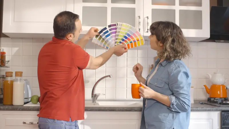 Man and woman choosing kitchen color with paint swatches.