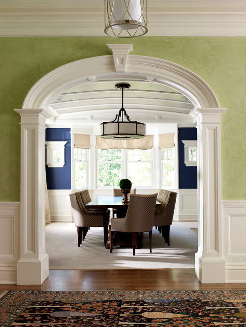Dining room framed by wall with green paint and white crown molding.