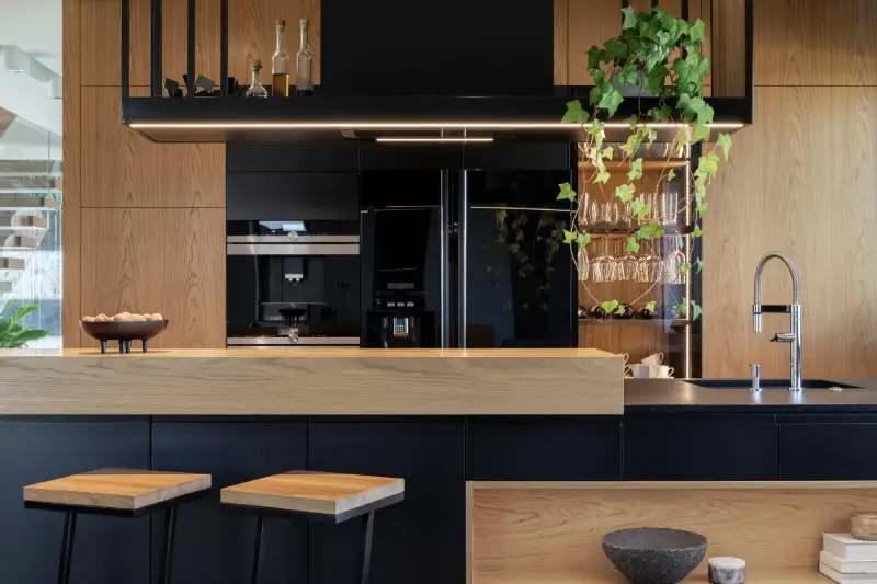 A modern kitchen with wood paneling on the counters and cabinets paired with black.