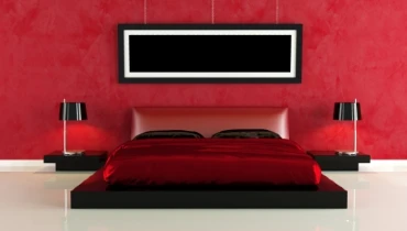 Photo of a bedroom with a red bed and red accent wall