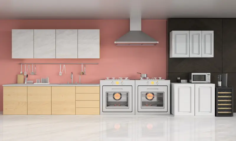 A modern kitchen with a pink wall and a black wall paired with white, marble, and wood cabinets and steel appliances.