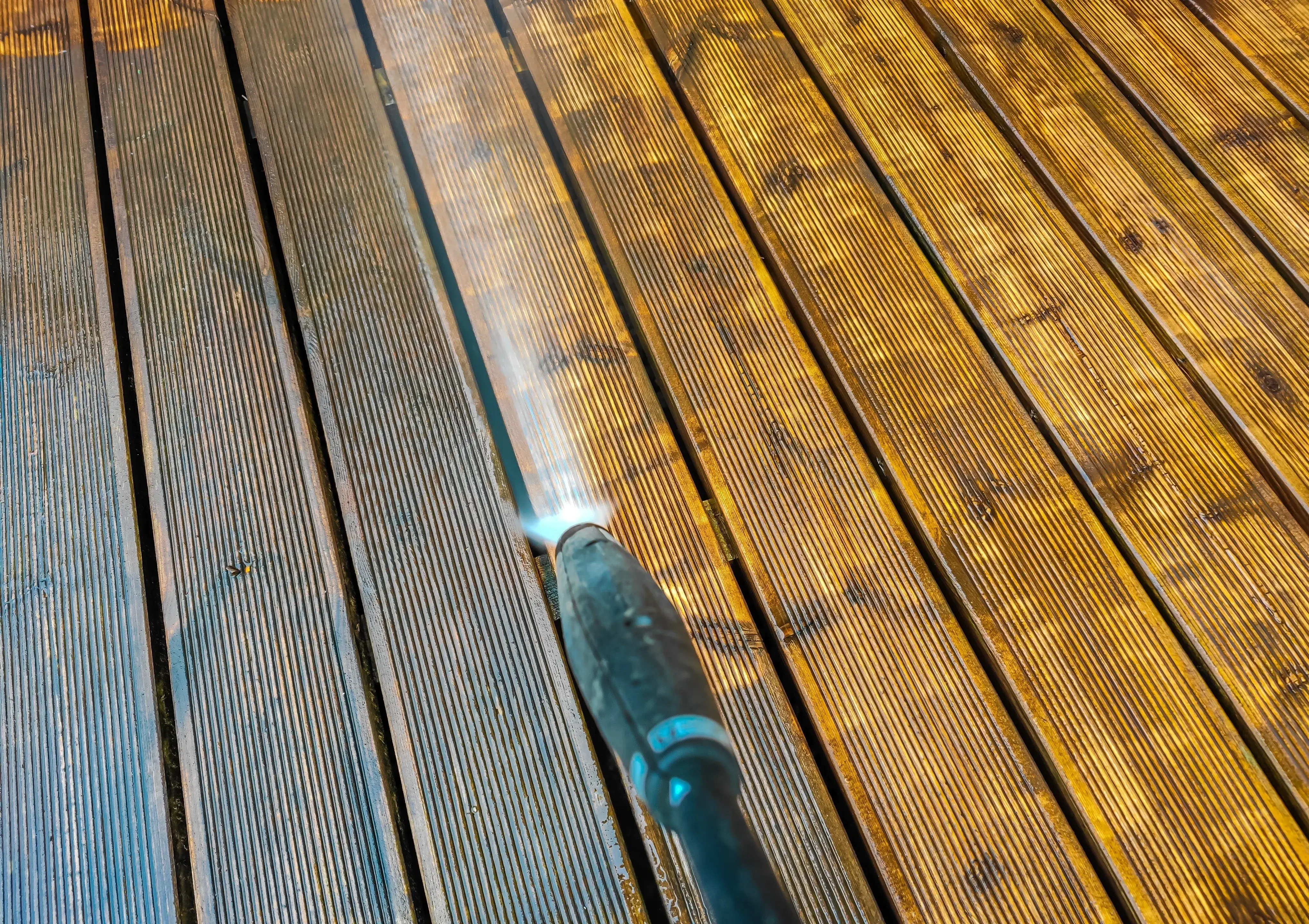 Pressure treated wood being cleaned with a high pressure water cleaner.
