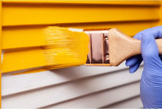 Image of someone painting vinyl siding.