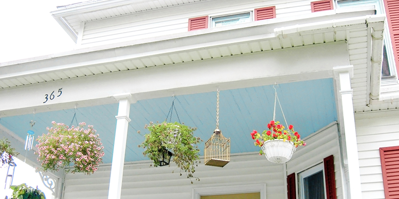 Photo of a porch ceiling painted sky blue on a two-story house.