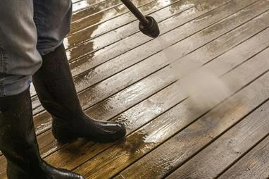 can you stain over painted wood, wood stain vs paint Person in boots power washing wooden deck.