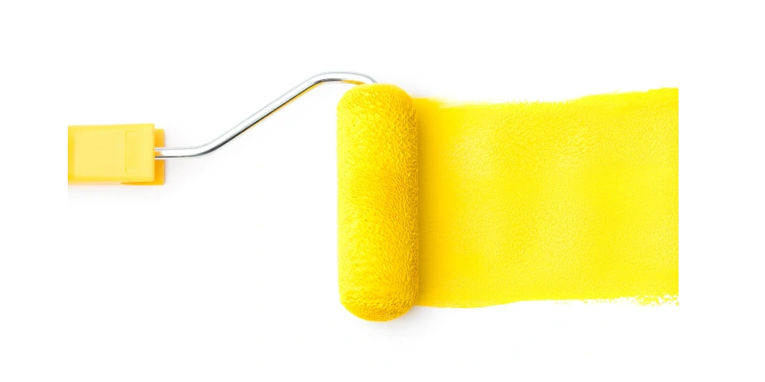 Yellow paint roller following a trail of yellow paint on a white background.