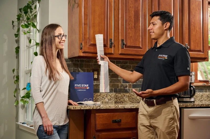 A Five Star Painting estimator showing a customer color swatches for her cabinets.