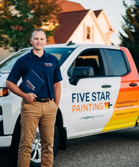 Male Five Star Painting service professional standing beside branded truck.