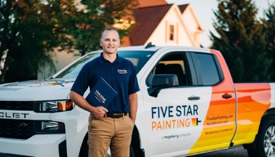 Male Five Star Painting service professional standing beside branded truck.