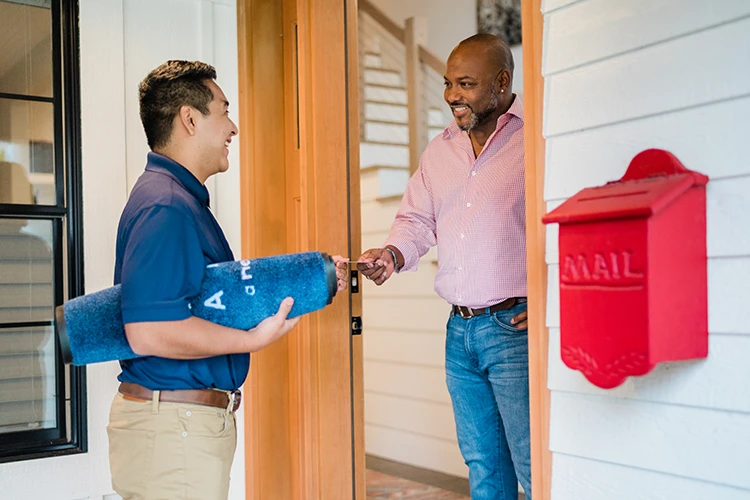 A Five Star Painting professional handing his business card to a customer.