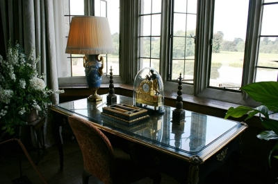 Man Cave Design: Decor Details Elegant desk with lamp, clock, and books by a window overlooking a tranquil landscape.