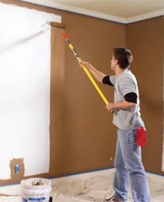 Painter with roller brush painting the wall brown.