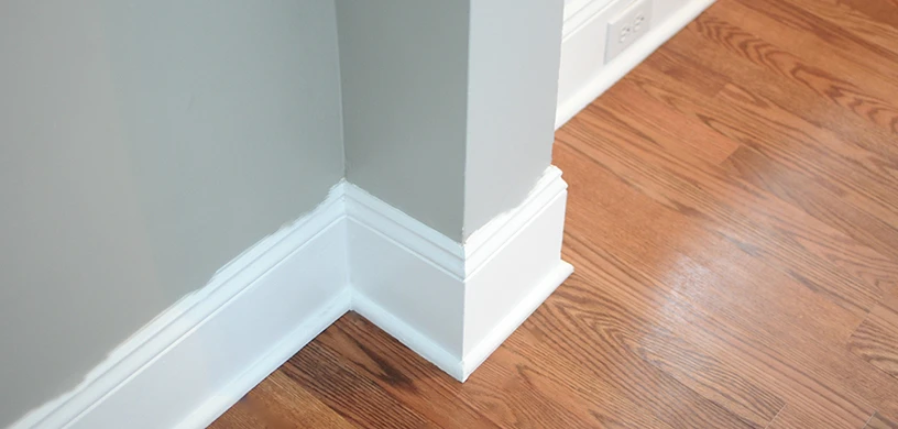 Picture of a sloppy, white paint trim against a grey wall.